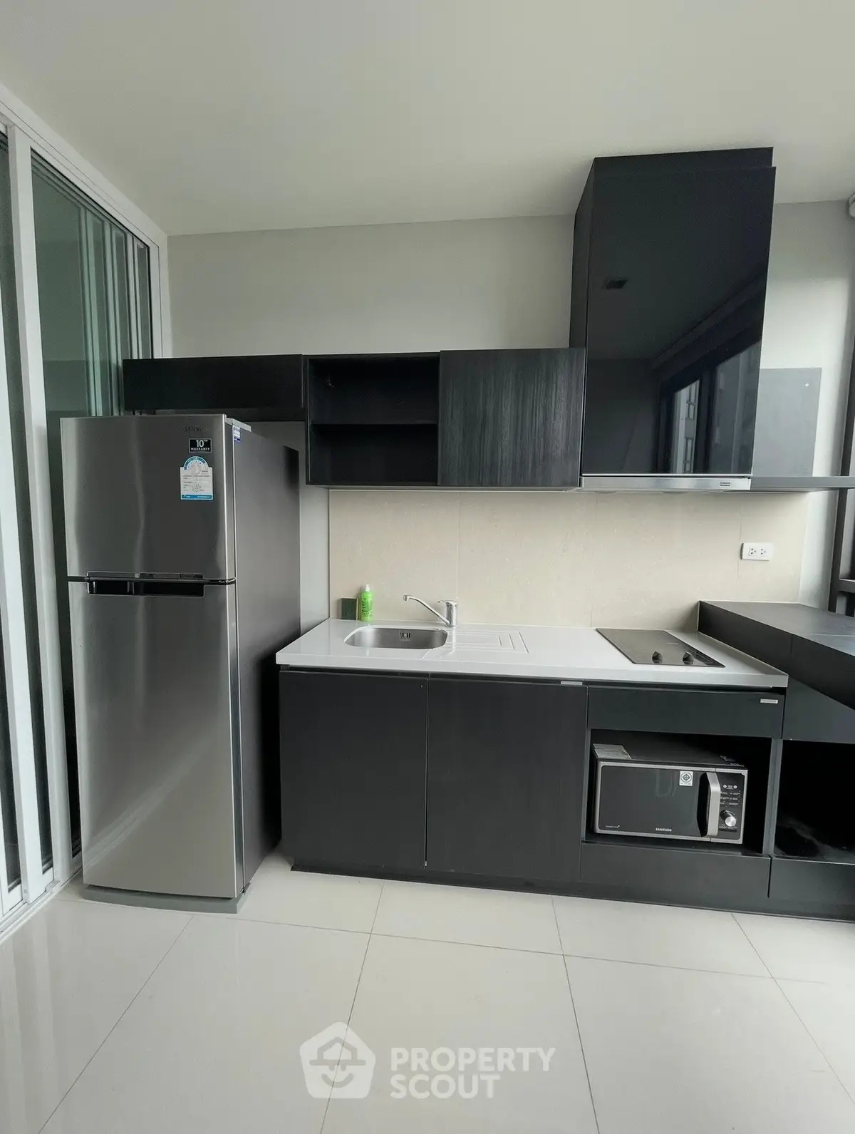 Modern kitchen with sleek black cabinetry and stainless steel appliances in a contemporary apartment.