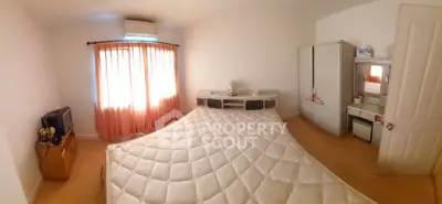 Spacious bedroom with natural light, featuring a large bed, wardrobe, and air conditioning.