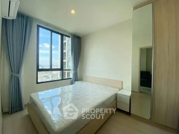 Bright bedroom with large window and city view, featuring modern furnishings and ample natural light.