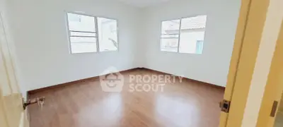 Spacious empty bedroom with wooden flooring and large windows for natural light.