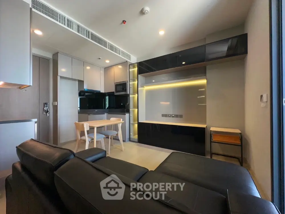 Modern living room with sleek black furniture and open kitchen layout