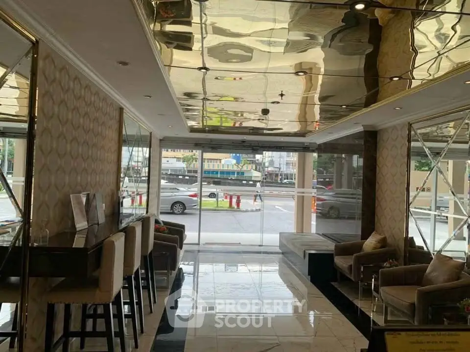 Luxurious lobby with modern decor and street view, featuring elegant seating and reflective ceiling.