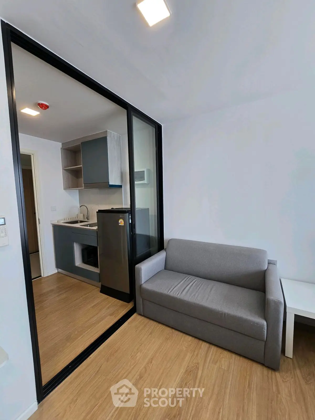 Modern compact living room with kitchenette and sleek glass partition
