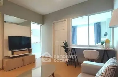 Modern living room with stylish decor and natural light, featuring a cozy seating area and a sleek TV setup.