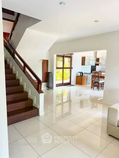 Spacious open-plan living area with elegant staircase and modern kitchen, perfect for family gatherings.