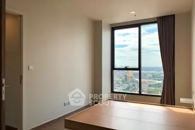Spacious bedroom with large window offering stunning city views in modern apartment.