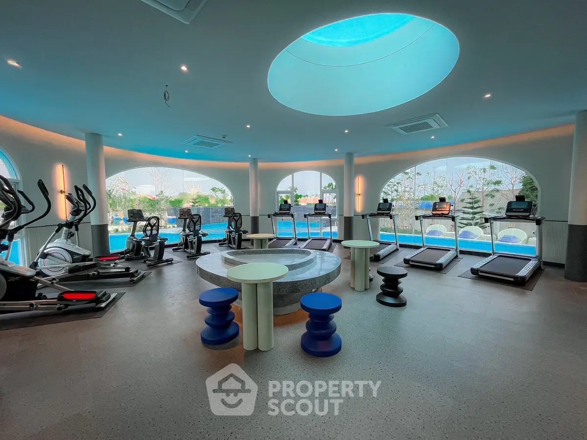 Luxurious gym with modern equipment and pool view, featuring elliptical machines and treadmills.