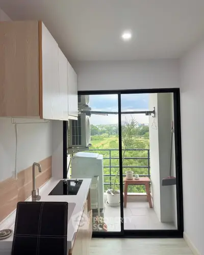 Modern kitchen with balcony view, featuring sleek cabinetry and compact design.