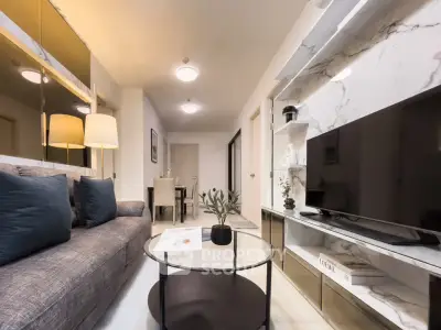 Modern living room with stylish decor and marble accents, featuring a cozy sofa and sleek TV setup.