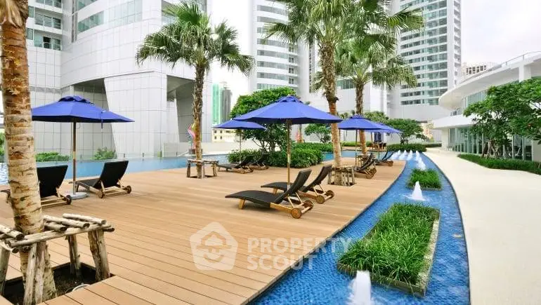 Luxurious poolside area with sun loungers and umbrellas in a modern high-rise complex.