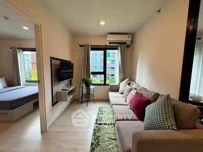 Modern living room with cozy sofa and wall-mounted TV, adjacent to a stylish bedroom with city view.