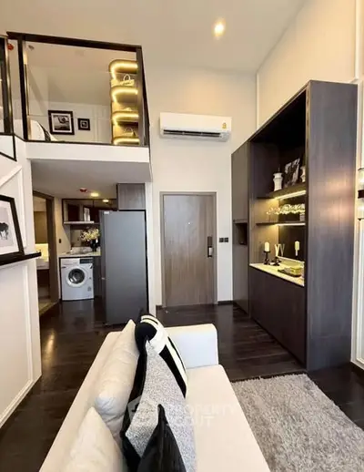 Modern duplex apartment with stylish living room and loft, featuring sleek decor and built-in shelving.