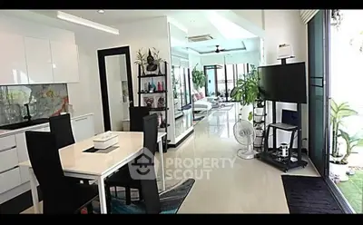 Spacious modern living room with open layout and stylish decor, featuring large windows and sleek furniture.