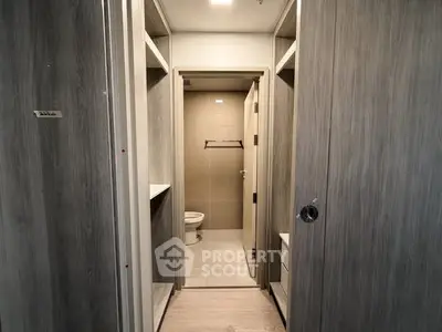 Modern bathroom with sleek wooden cabinetry and neutral tile flooring.