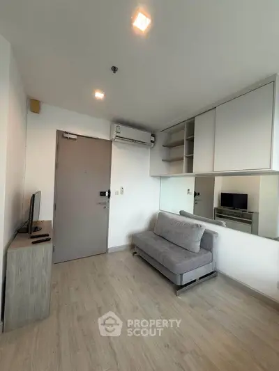 Modern living room with sleek design, featuring a cozy sofa and wall-mounted air conditioning.