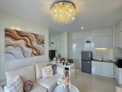Modern living room with elegant chandelier and sleek kitchen in open layout apartment.