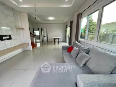 Spacious modern living room with large windows and stylish gray sofa