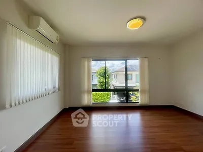 Spacious empty room with large window and wooden flooring