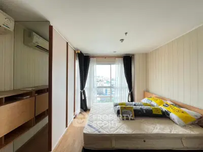 Cozy bedroom with large window and city view, featuring a comfortable bed and stylish wooden furniture.