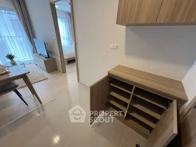 Modern apartment interior with open living room and bedroom view, featuring stylish wooden cabinetry.
