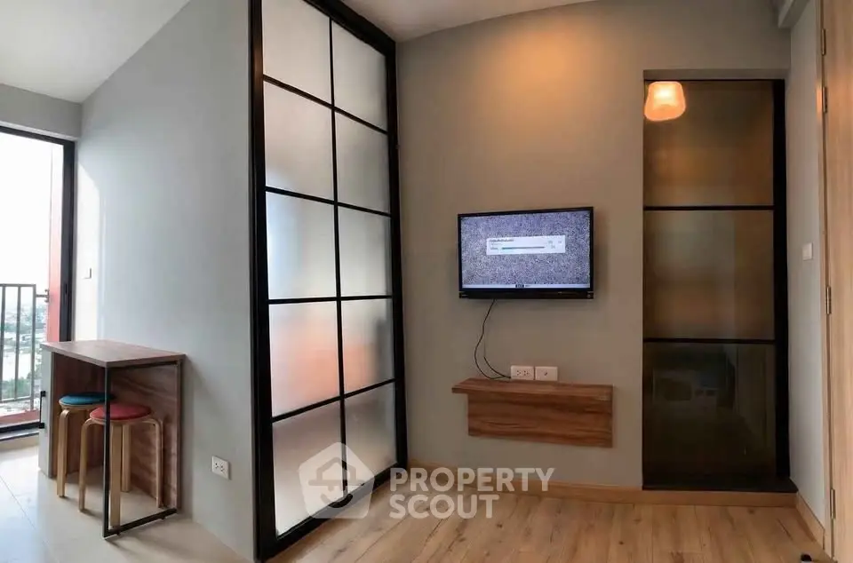 Modern living room with stylish partition and mounted TV, featuring a cozy seating area and natural light.