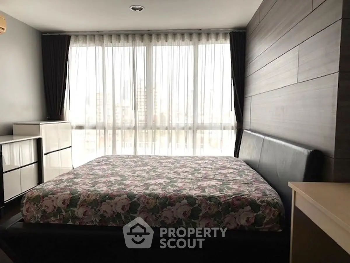 Spacious bedroom with large windows and modern decor in urban apartment