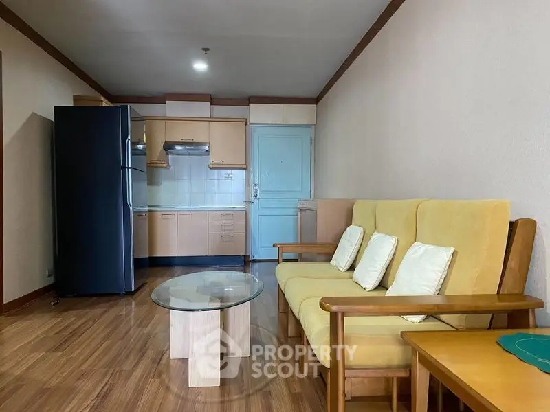 Cozy living room with modern kitchen, featuring wooden flooring and stylish furniture.
