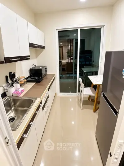 Modern kitchen with sleek cabinetry and stainless steel appliances in a cozy apartment.