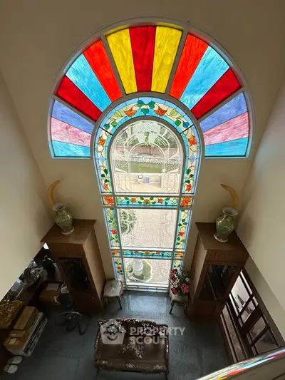 Stunning stained glass window in elegant living room with high ceiling and classic decor.