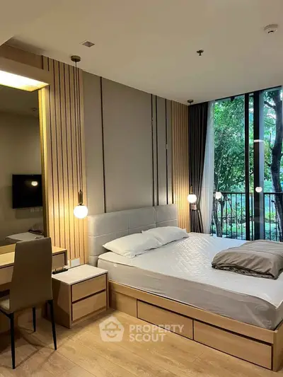 Modern bedroom with elegant design and large window overlooking lush greenery, featuring stylish lighting and wooden accents.