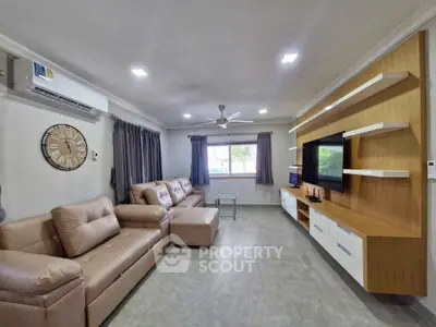 Spacious modern living room with elegant furniture and wall-mounted TV, perfect for family gatherings.