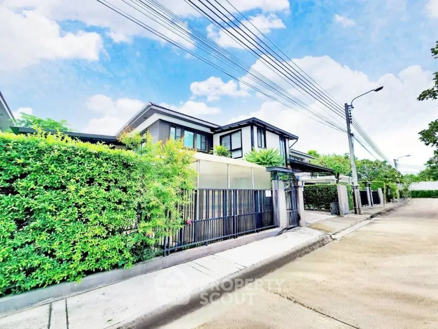 Modern two-story house with lush greenery and sleek design on a sunny day.