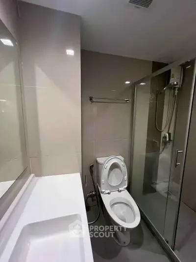 Modern bathroom with sleek design featuring a glass shower enclosure and contemporary fixtures.