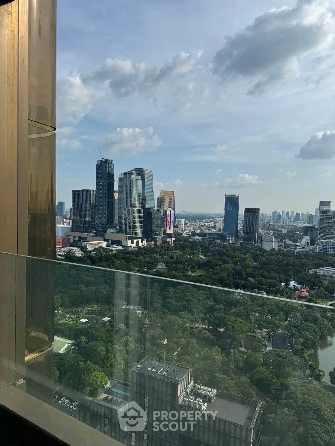 Stunning cityscape view from a high-rise balcony overlooking lush greenery and skyscrapers.