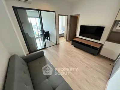 Modern living room with sleek furniture and large TV, adjacent to dining area and bedroom.