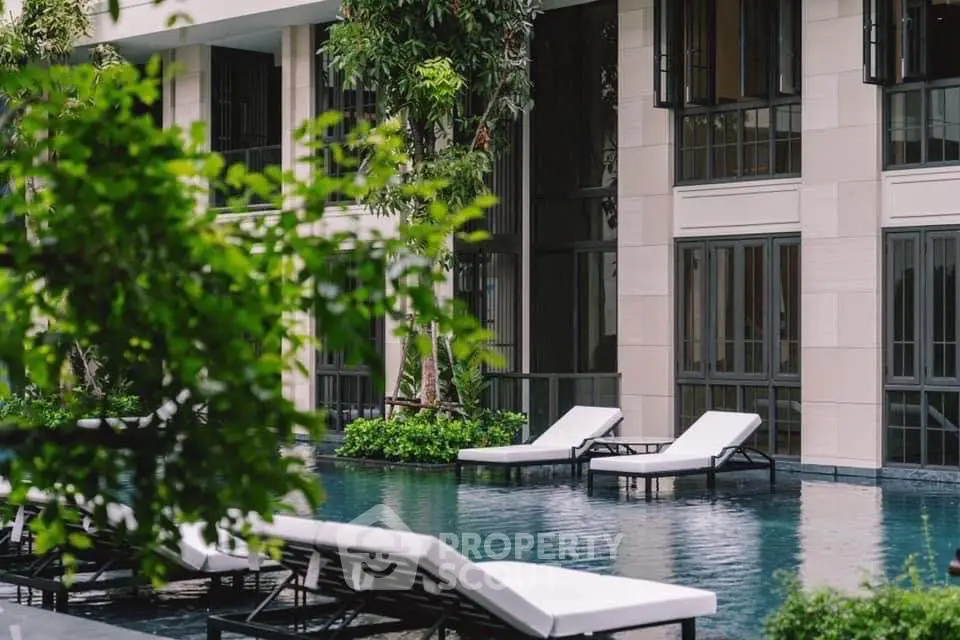 Luxurious poolside area with modern lounge chairs and lush greenery at a high-end residential building.