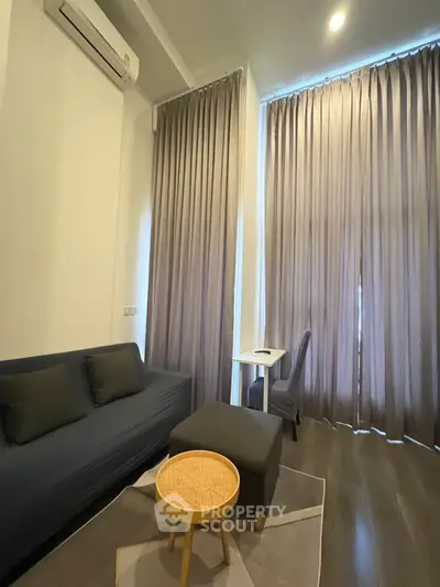 Modern living room with sleek furniture and floor-to-ceiling curtains, featuring a cozy seating area and stylish decor.
