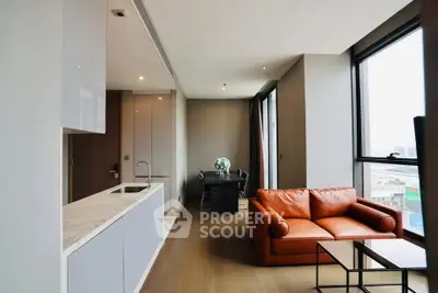 Modern living room with open kitchen and large windows offering city views.