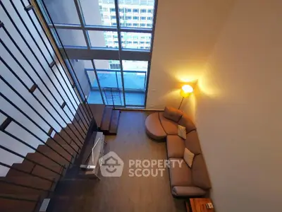 Spacious modern living room with high ceilings and large windows offering city views.