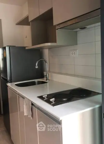 Modern compact kitchen with sleek cabinetry and electric stove in urban apartment
