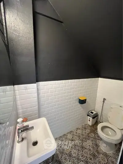 Charming attic bathroom with modern fixtures and stylish tile flooring.
