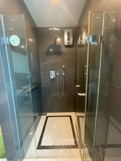 Modern bathroom with glass shower doors and sleek black tiles