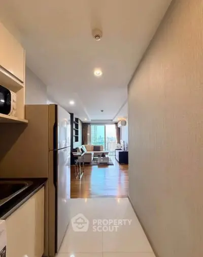 Modern open-layout kitchen leading to a stylish living room with a city view.