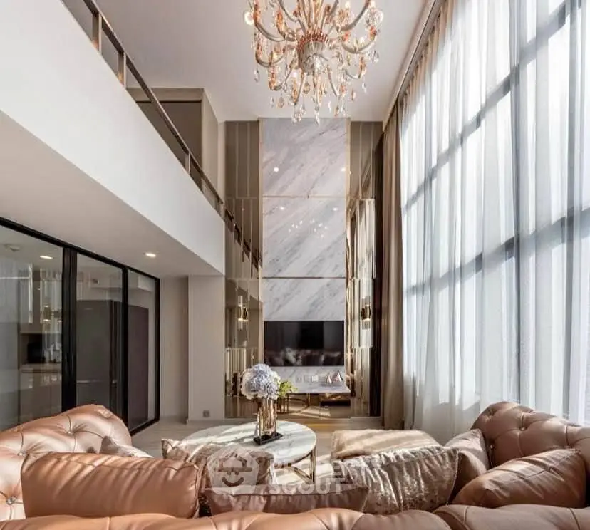Luxurious living room with high ceilings, elegant chandelier, and floor-to-ceiling windows.