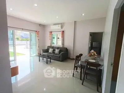 Spacious living room with modern decor and dining area, featuring large windows and natural light.