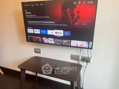 Modern living room with wall-mounted smart TV and sleek wooden table.