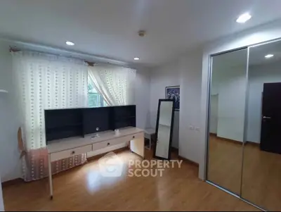 Spacious bedroom with wooden flooring and mirrored closet doors, perfect for modern living.