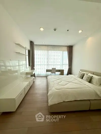 Spacious modern bedroom with large window and elegant furnishings