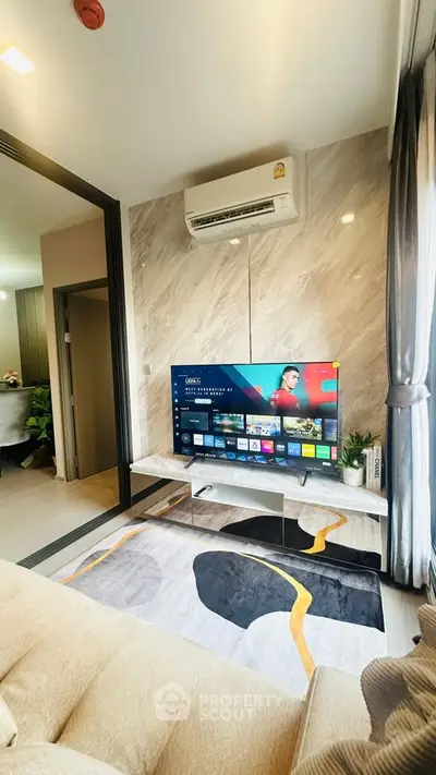 Modern living room with stylish decor and wall-mounted TV, featuring a cozy ambiance and sleek air conditioning unit.