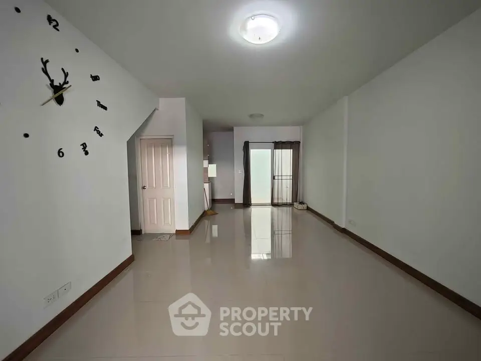 Spacious empty living room with modern wall clock and glossy floor tiles